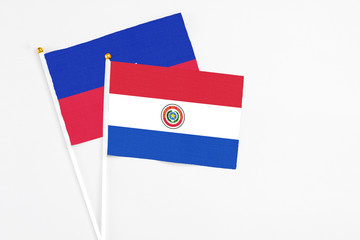 Paraguay and Haiti stick flags on white background. High quality fabric, miniature national flag. Peaceful global concept.White floor for copy space.