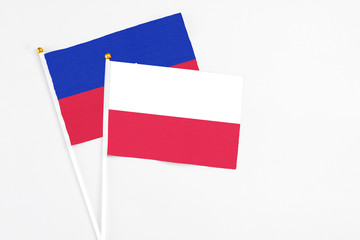 Poland and Haiti stick flags on white background. High quality fabric, miniature national flag. Peaceful global concept.White floor for copy space.