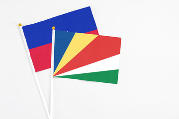 Seychelles and Haiti stick flags on white background. High quality fabric, miniature national flag. Peaceful global concept.White floor for copy space.