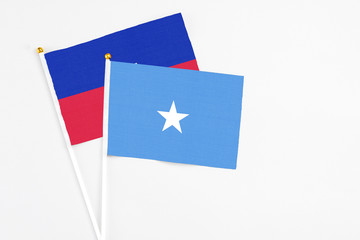 Somalia and Haiti stick flags on white background. High quality fabric, miniature national flag. Peaceful global concept.White floor for copy space.