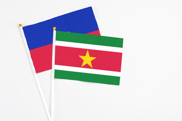 Suriname and Haiti stick flags on white background. High quality fabric, miniature national flag. Peaceful global concept.White floor for copy space.