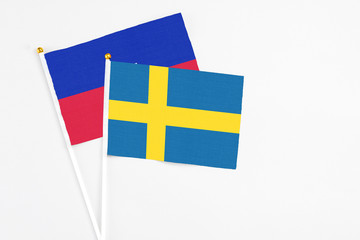 Sweden and Haiti stick flags on white background. High quality fabric, miniature national flag. Peaceful global concept.White floor for copy space.