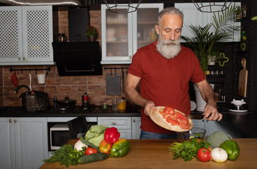 Bearded senior man chopping vegetables in the kitchen.