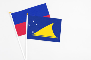 Tokelau and Haiti stick flags on white background. High quality fabric, miniature national flag. Peaceful global concept.White floor for copy space.