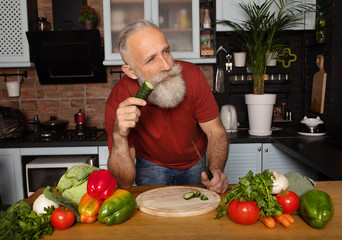 Bearded senior Man preparing healthy and tasty salad in kitchen.