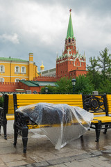 a beggar sleeps on a yellow bench in the heart of Moscow near the Kremlin, covered from the rain with plastic wrap. corruption in the country, population decline, degradation of society.