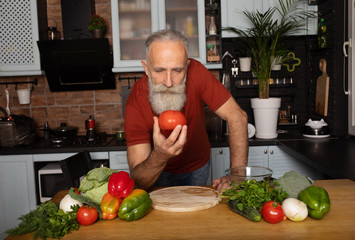 Bearded senior Man preparing healthy and tasty salad in kitchen.