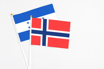 Obraz premium Bouvet Islands and Honduras stick flags on white background. High quality fabric, miniature national flag. Peaceful global concept.White floor for copy space.