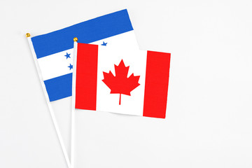 Canada and Honduras stick flags on white background. High quality fabric, miniature national flag. Peaceful global concept.White floor for copy space.