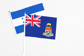 Cayman Islands and Honduras stick flags on white background. High quality fabric, miniature national flag. Peaceful global concept.White floor for copy space.