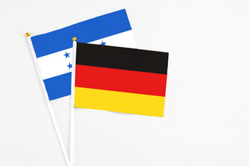 Germany and Honduras stick flags on white background. High quality fabric, miniature national flag. Peaceful global concept.White floor for copy space.