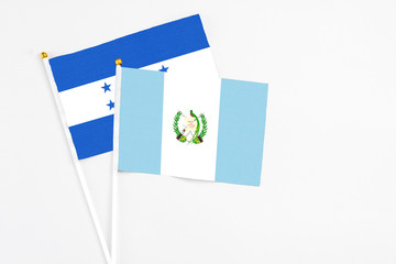 Guatemala and Honduras stick flags on white background. High quality fabric, miniature national flag. Peaceful global concept.White floor for copy space.