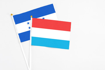 Luxembourg and Honduras stick flags on white background. High quality fabric, miniature national flag. Peaceful global concept.White floor for copy space.