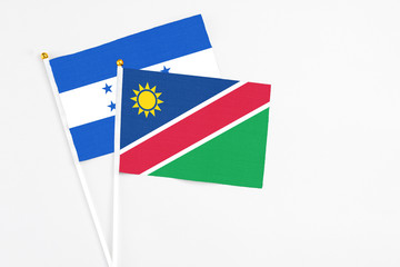 Namibia and Honduras stick flags on white background. High quality fabric, miniature national flag. Peaceful global concept.White floor for copy space.