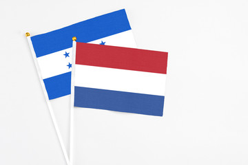 Netherlands and Honduras stick flags on white background. High quality fabric, miniature national flag. Peaceful global concept.White floor for copy space.