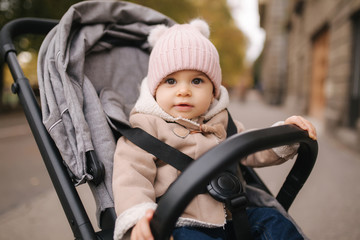Cute little baby in pram. Adorable baby girl in autumn sitting in her pram