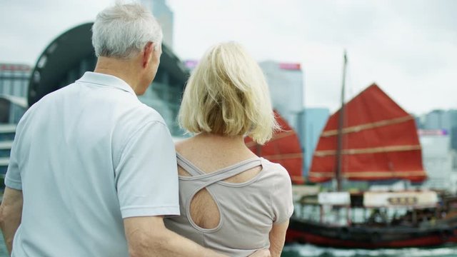 Retirement couple passing red sail Junk Hong Kong 