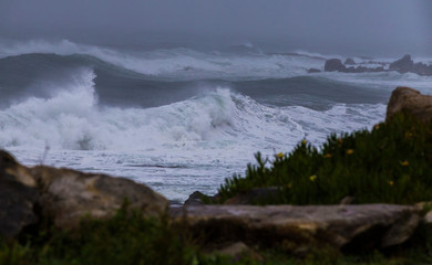 Storm at sea, storm warning on the coast. Thunderclouds and big sea waves during a storm. Restless sea during the rain.