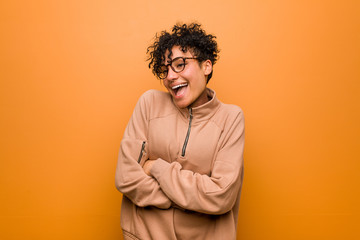 Fototapeta na wymiar Young mixed african american woman against a brown background laughing and having fun.