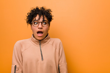 Fototapeta na wymiar Young mixed african american woman against a brown background being shocked because of something she has seen.