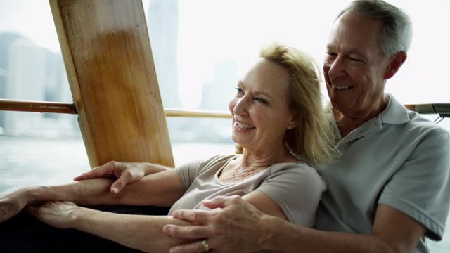 Happy couple enjoying retirement cruise Hong Kong harbour 