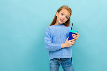 Copyspace photo of girl in a blue sweater against a blue wall with a glass of cocoa