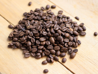 Fototapeta na wymiar Black coffee grains lie on a brown wooden table, background