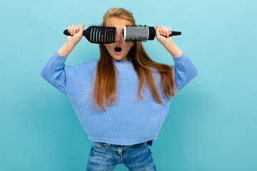 portrait of a cheerful contented shkolnitsa with hairbrushes in her hands on a blue background, closes her eyes with hairbrushes, fools around