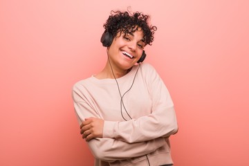 Young african american woman listening to music smiling confident with crossed arms.