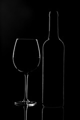 Empty wine glass and a bottle isolated on a dark background