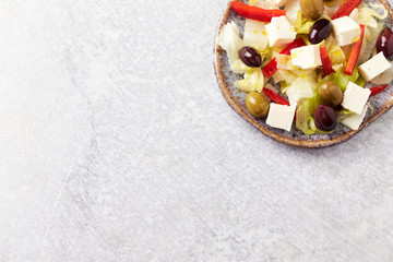 Obraz na płótnie Canvas Salad with Green and Kalamata Olives, Red Pepper and Feta Cheese on Bright Stone Background. Healthy Snack Idea. Top view. Copy space. 