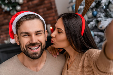 Portrait of lovely couple making selfie with their smartphone enjoy christmas time at home