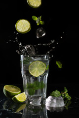 Mojito cocktail on black background with flying ingredients
