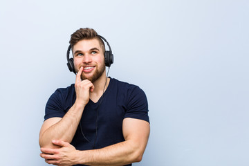 Young caucasian man listening to music relaxed thinking about something looking at a copy space.