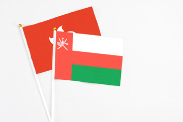 Oman and Hong Kong stick flags on white background. High quality fabric, miniature national flag. Peaceful global concept.White floor for copy space.