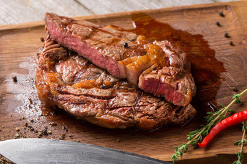 Cut Rib eye steak on wooden board, closeup