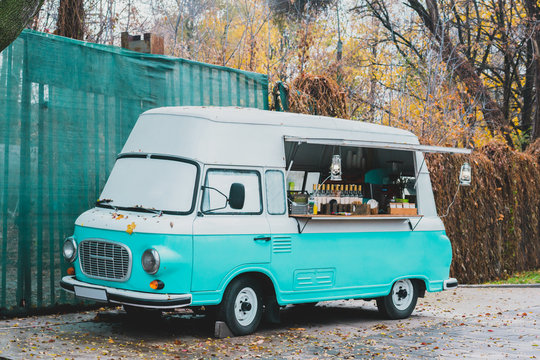 Turquoise and white street food retro van in the autumn's park sells coffee. Business. Work. Outdoor. Entrepreneur. Mobile coffee truck