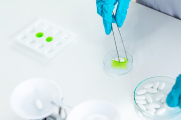 scientist wearing lab coat and gloves taking a sample in laboratory