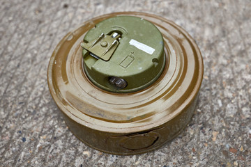 Khaki colour modern anti-tank mine lies on concrete surface