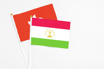 Tajikistan and Hong Kong stick flags on white background. High quality fabric, miniature national flag. Peaceful global concept.White floor for copy space.