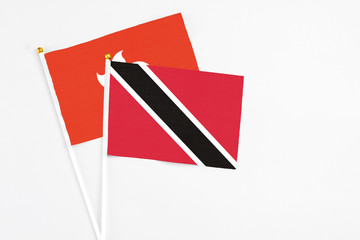 Trinidad And Tobago and Hong Kong stick flags on white background. High quality fabric, miniature national flag. Peaceful global concept.White floor for copy space.