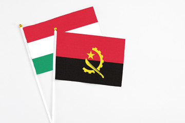 Angola and Hungary stick flags on white background. High quality fabric, miniature national flag. Peaceful global concept.White floor for copy space.