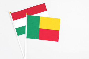 Benin and Hungary stick flags on white background. High quality fabric, miniature national flag. Peaceful global concept.White floor for copy space.