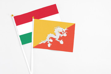 Bhutan and Hungary stick flags on white background. High quality fabric, miniature national flag. Peaceful global concept.White floor for copy space.