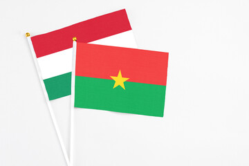 Burkina Faso and Hungary stick flags on white background. High quality fabric, miniature national flag. Peaceful global concept.White floor for copy space.