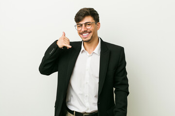 Young business hispanic man showing a mobile phone call gesture with fingers.