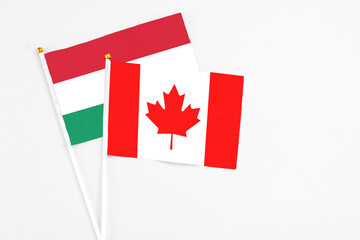 Canada and Hungary stick flags on white background. High quality fabric, miniature national flag. Peaceful global concept.White floor for copy space.