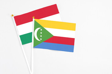 Comoros and Hungary stick flags on white background. High quality fabric, miniature national flag. Peaceful global concept.White floor for copy space.