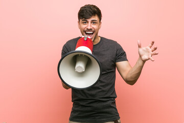 Young hispanic man holding a megaphone celebrating a victory or success