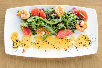 Delicious dish with grilled shrimps, slice grapefruit and arugula salad and spicy fried prawns. Restaurant menu, natural and organic food concept.